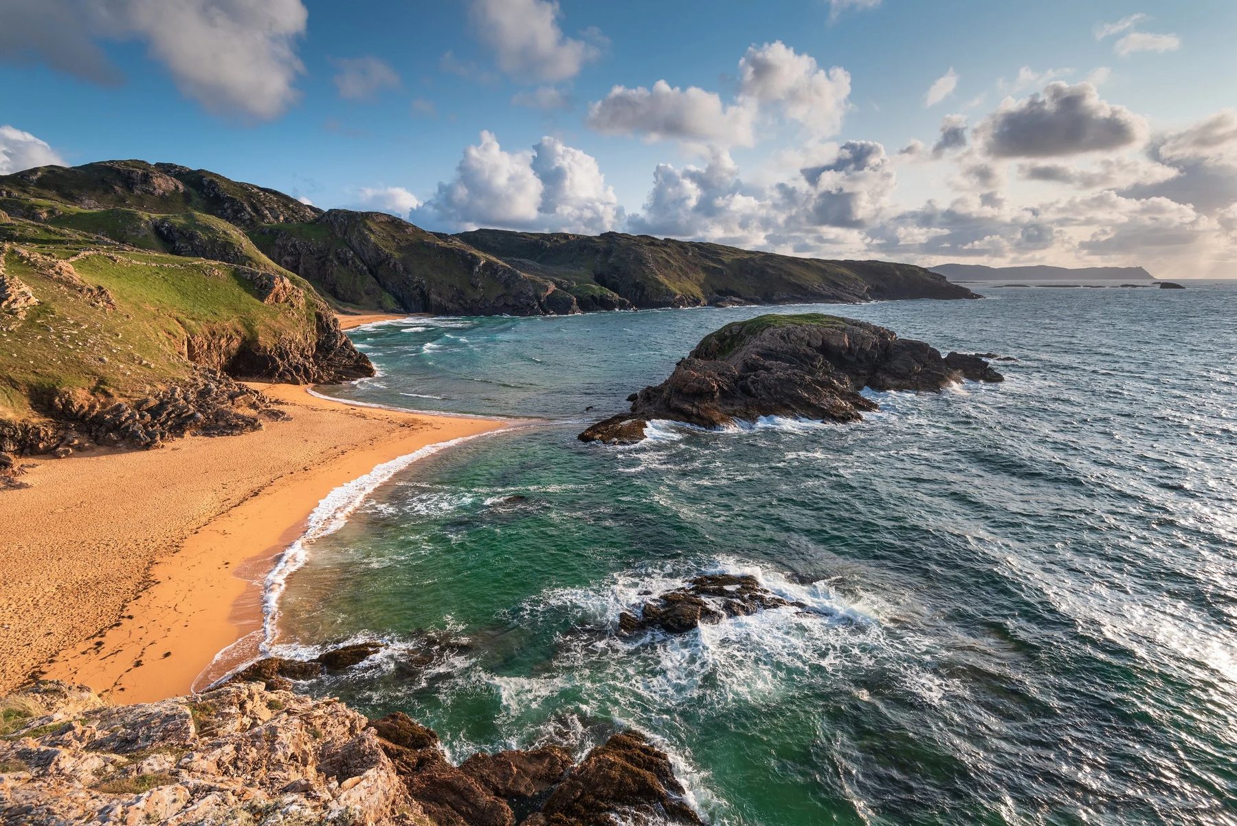 Sunlight on a sandy cove and green headland at Melmore, Rosguill, Co. Donegal