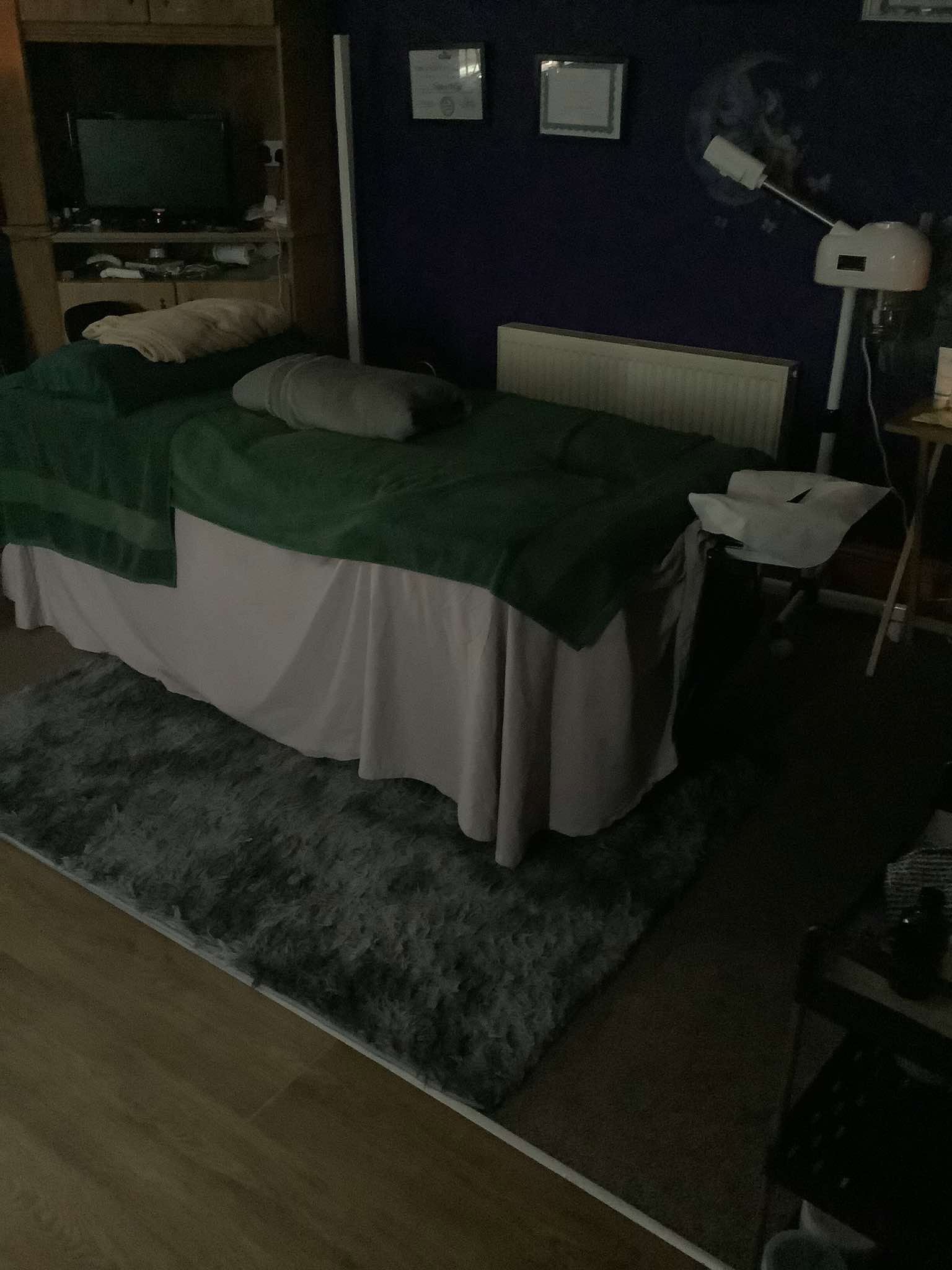 Massage table set up with a green throw in a treatment room