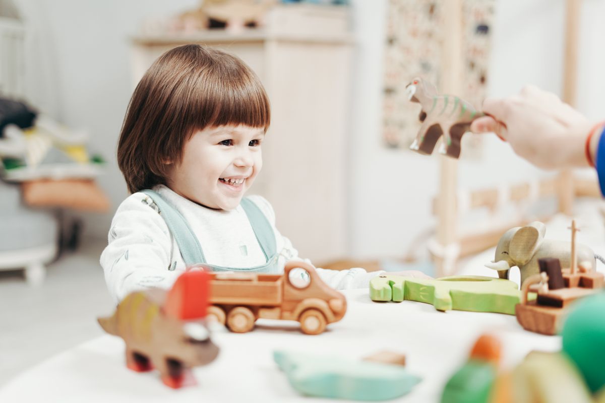 Smiling toddler playing with wooden toy animals